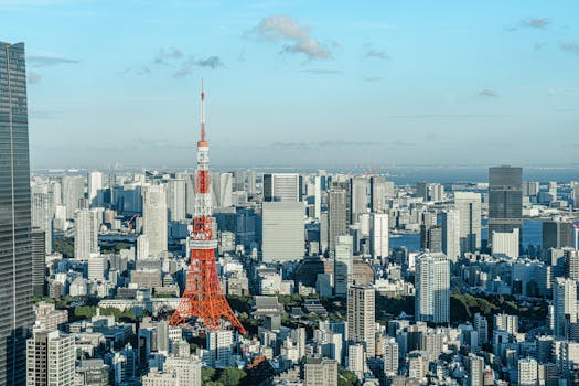 Elevated view of Tokyo cityscape with the iconic Tokyo Tower under a clear blue sky.